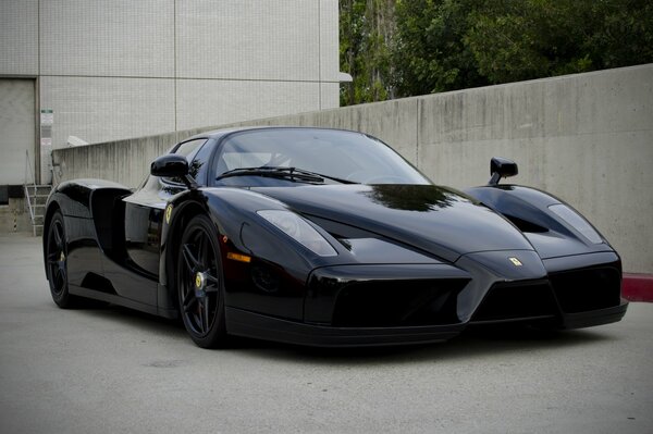 Un Ferrari negro se encuentra frente a un edificio de concreto