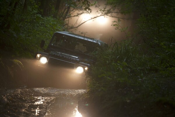 SUV nel bosco nel fango con i fari accesi