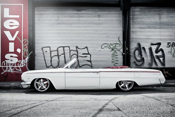 Elegante Chevrolet Impala convertible blanco con fondo de graffiti