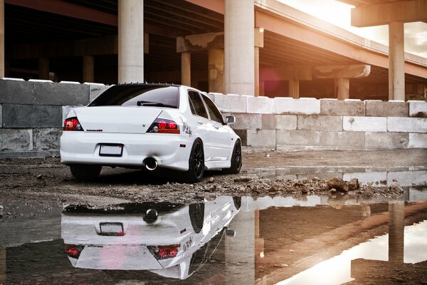 A white car on the background of a building next to a puddle