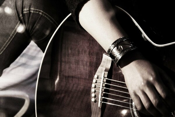 Hand with a bracelet on the stun on the guitar