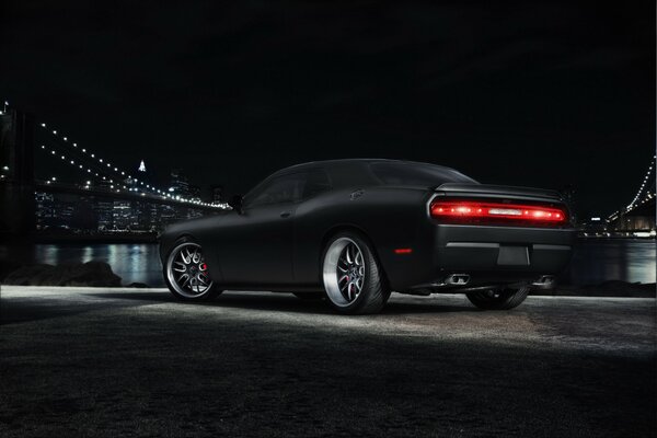 Dodge Challenger noir sur fond de métropole avec pont