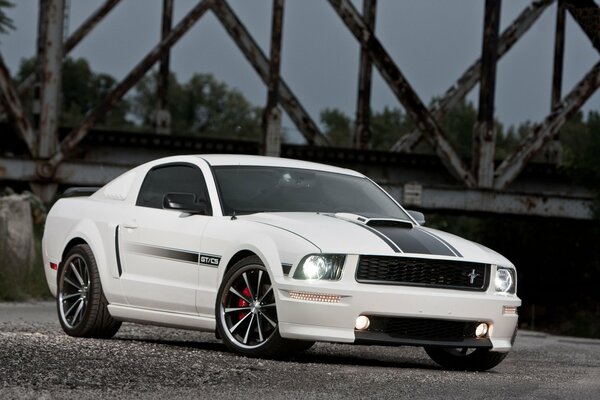 White Ford Mustang drives past the bridge