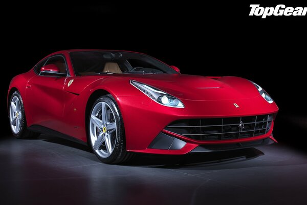 Une Ferrari F12 berlinetta rouge se tient dans la pénombre