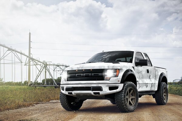 Una camioneta Ford F-150 de camuflaje se encuentra en la carretera junto a la línea eléctrica