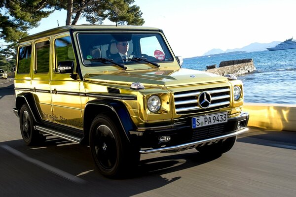 Ein goldener Mercedes-Jeep fährt die Küste entlang