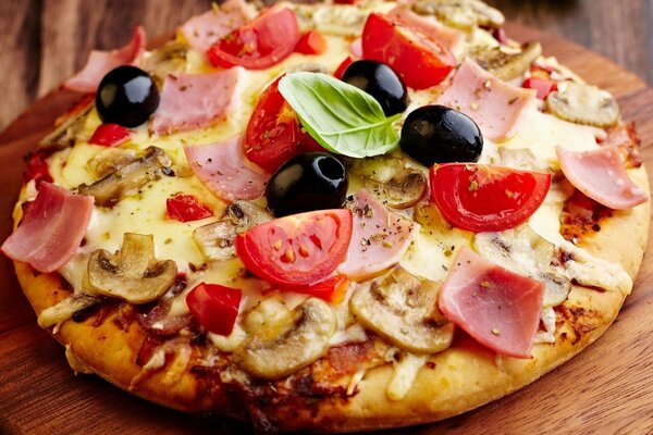 Delicious pizza with tomatoes, ham, mushrooms and olives