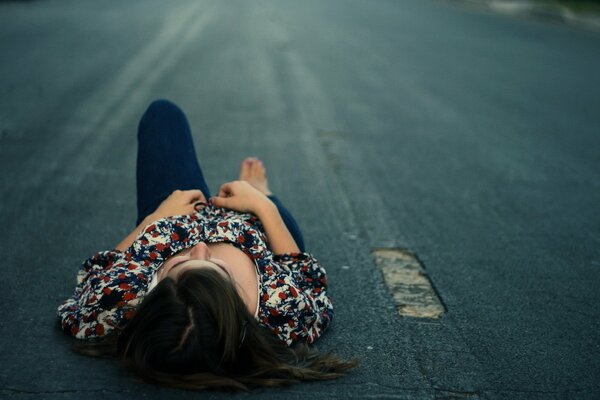 The girl is lying on the roadway