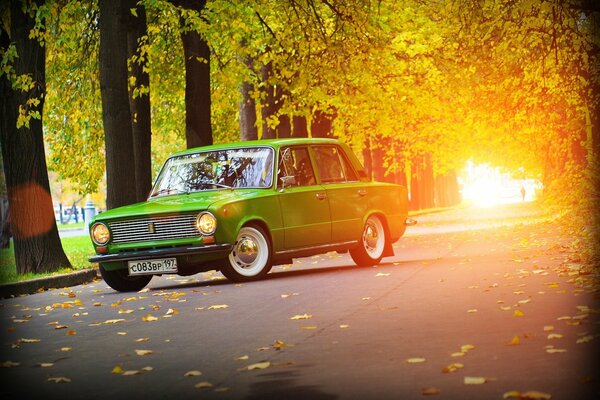 Green Lada car on the background of an autumn road