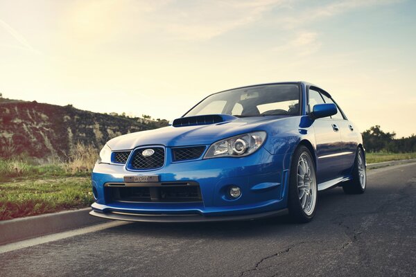 Subaru Impreza bleu sur la piste au milieu des collines