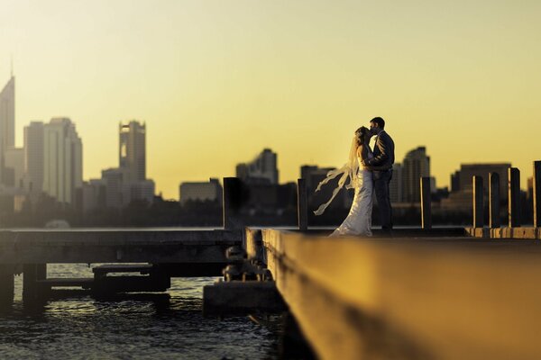 Newlyweds kiss on the pier during sunset