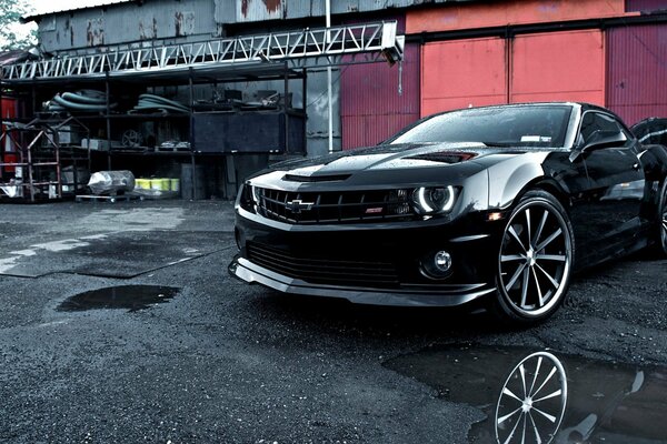 Coche deportivo negro en el fondo de garajes y neumáticos