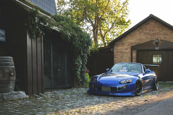 Front view of the blue honda s2000 on the background of the house