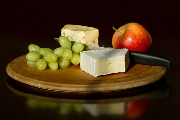 There are two types of cheese and fruit on the table