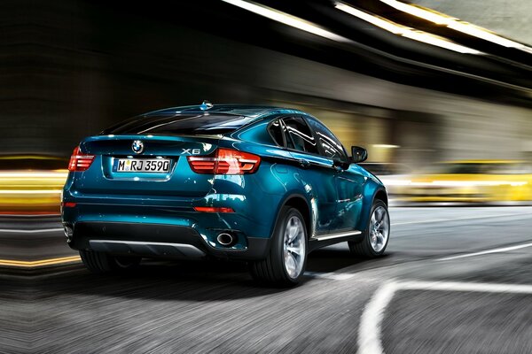 La bella bmw X6 blu corre lungo la strada