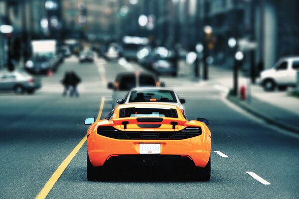 A yellow sports car rides in a column on a busy road