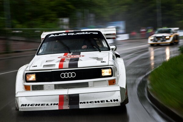 Audi blanco en el tráfico en la carretera mojada