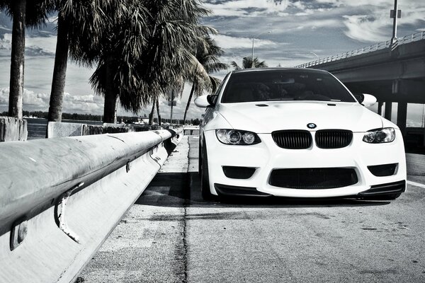 Une BMW blanche arrêtée près d une clôture sur un pont