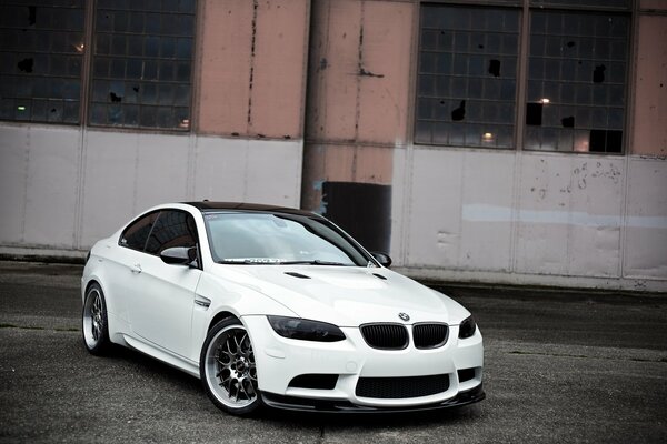 Blanco hermoso BMW con edificio abandonado