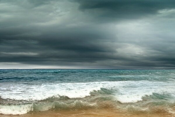 Das Meer spritzt bei einem Gewitter Wellen auf den Sand