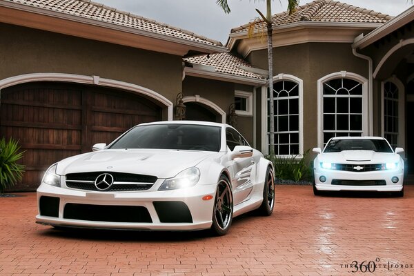 White Mercedes and Chevrolet on the background of the house