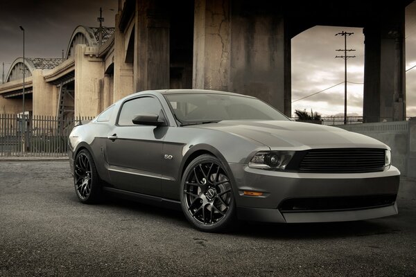 Mustang car near the fence under the bridge