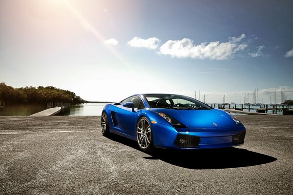 Blauer Lamborghini auf dem Hintergrund von Wasser, Pier und Himmel