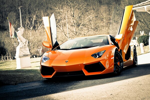 Voiture orange Lamborghini avec portes ouvertes sur la route