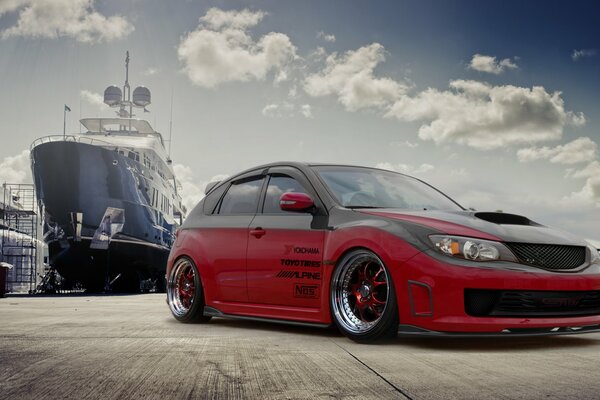 Red Subaru impreza on the background of the ship