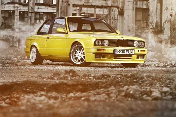 Жёлтый заниженный BMW 3 серии E30 на фоне руин