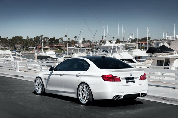 Elegante bmw serie 5 blanco en el muelle con yates