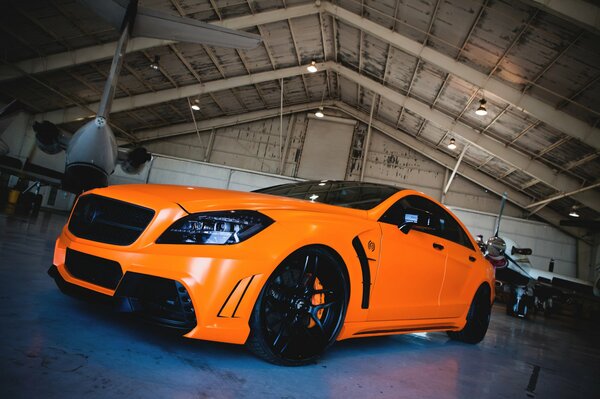 Mercedes-benz naranja en el hangar con el avión