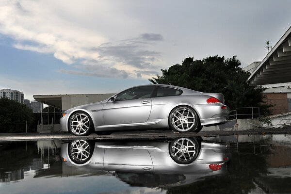 Silver BMW with reflection in a puddle