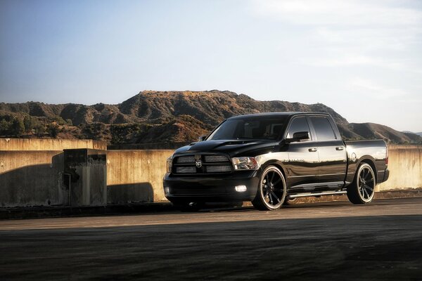 Black pickup truck rides on the background of mountains