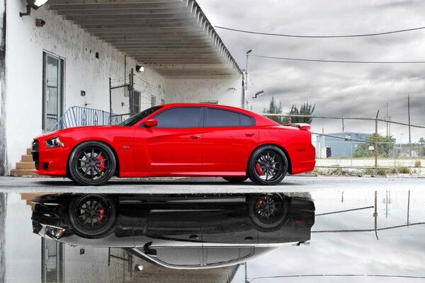 El Dodge rojo brillante se levanta y se refleja en el charco