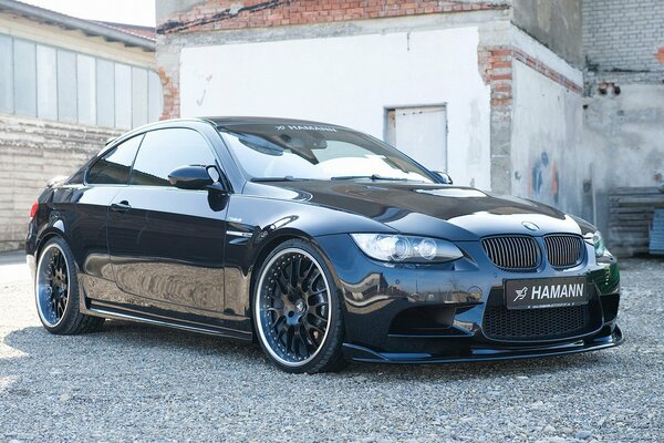 El BMW M3 Hamann negro se encuentra en el fondo de la pared con mampostería rota