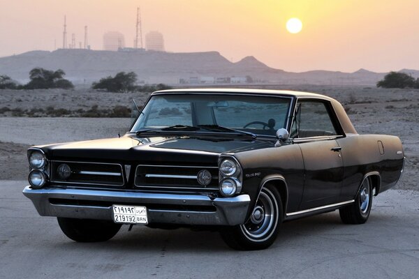 Un Pontiac retro de 1963 en una carretera desierta bajo el sol