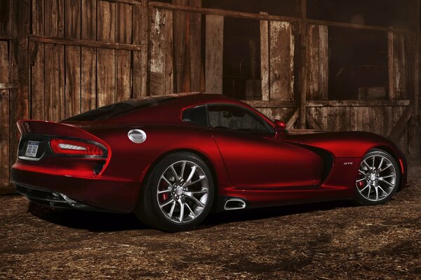 Red supercar near a wooden building