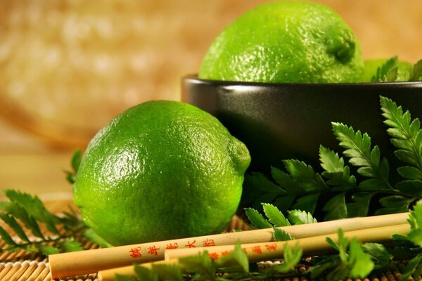 Limes in a cup next to Chinese chopsticks