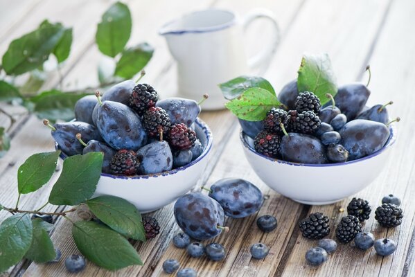 Still life purple fruits blackberries and plums in white cups