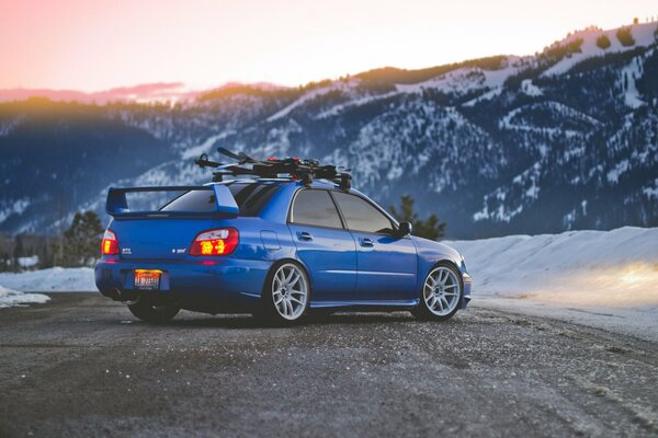 Subaru blu sullo sfondo di un paesaggio montano invernale