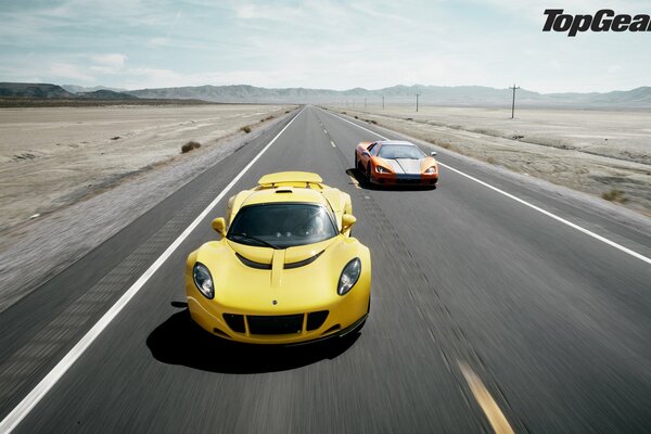 Two sports cars driving on a straight track