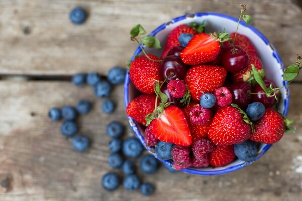 Strawberries, raspberries, blueberries in a deep cup