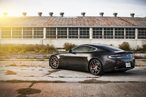 The back of a black aston martin vantage on the background of a hangar