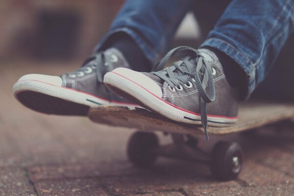 Skateboard on the asphalt, feet in sneakers