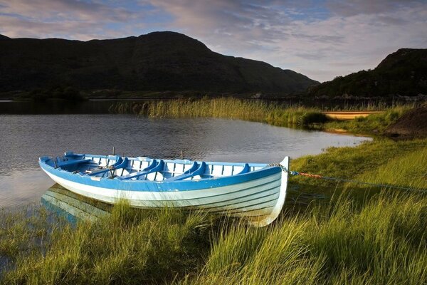 Ein ordentliches blau-weißes Boot hat sich am Ufer eines Bergsees festgemacht