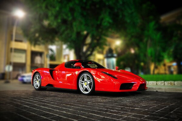 Ferrari rojo brillante en el estacionamiento en el fondo de la ciudad nocturna