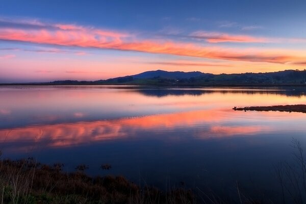 Lac bleu se fondant avec le ciel au coucher du soleil