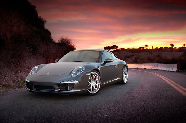 The powder car stands in the middle of the road near the mountain against the backdrop of a California sunset