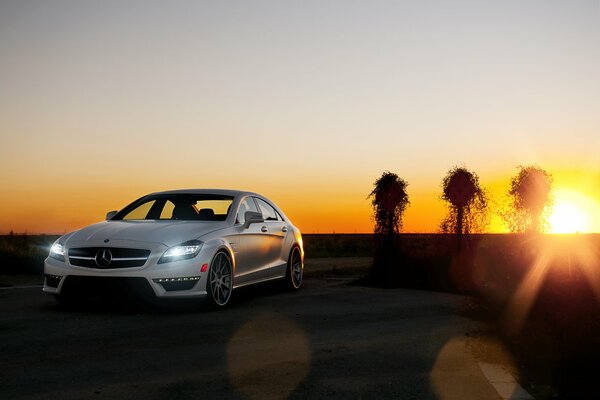 Un Mercedes Benz blanco como la nieve se para al atardecer